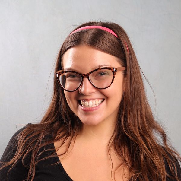 Smiling woman with glasses and pink headband.