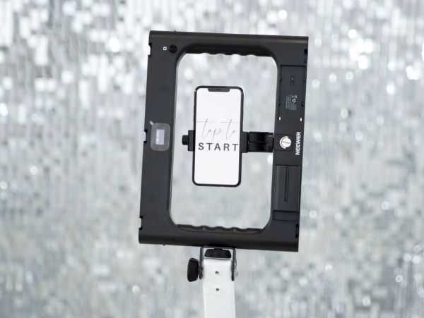 A phone on a stand with a 'tap to start' message and silver disco balls background.