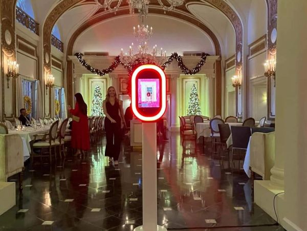 Elegant dining hall decorated for Christmas with people and a photo booth.