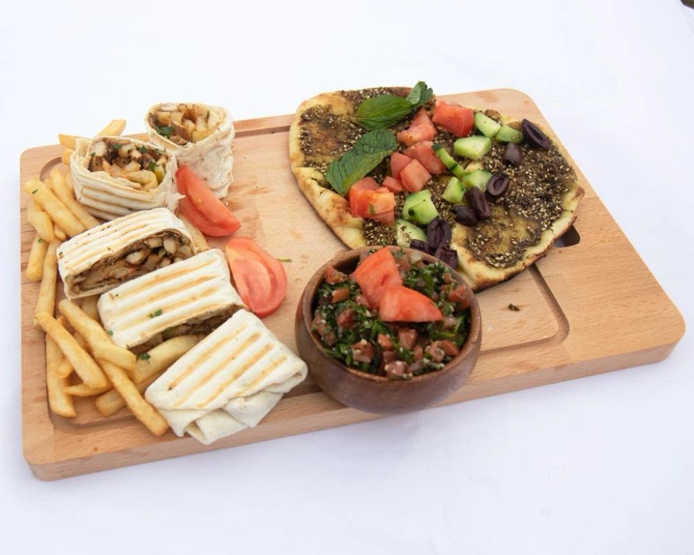 Wraps, french fries, manouche and tabbouleh on a wooden board
