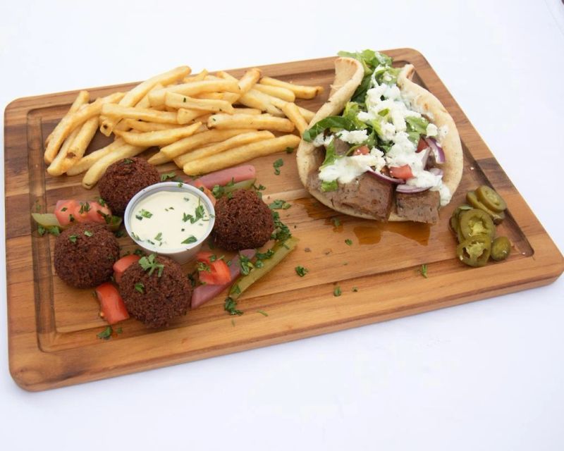 Falafel, a wrap and french fries on a wooden board