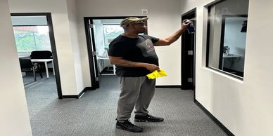 Man cleaning a glass surface with a cloth and spray bottle.