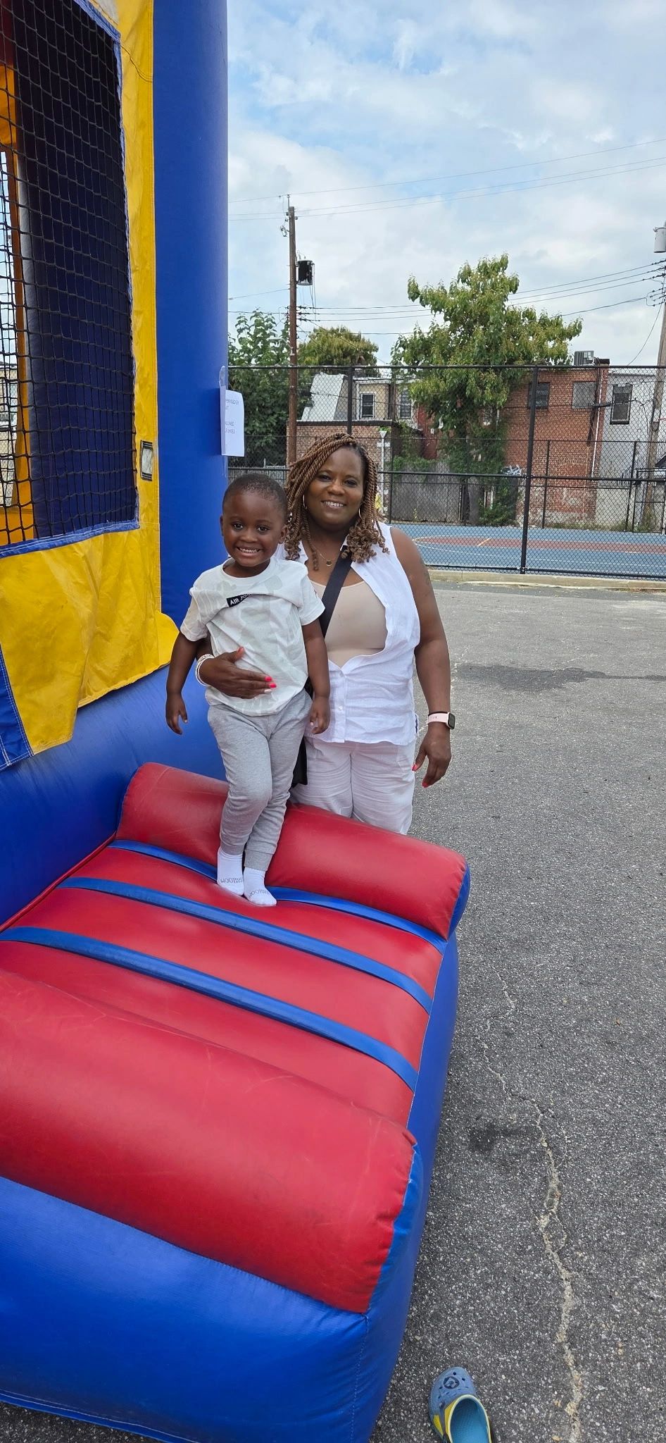 A woman and a child smiling by a colorful inflatable structure outdoors.
