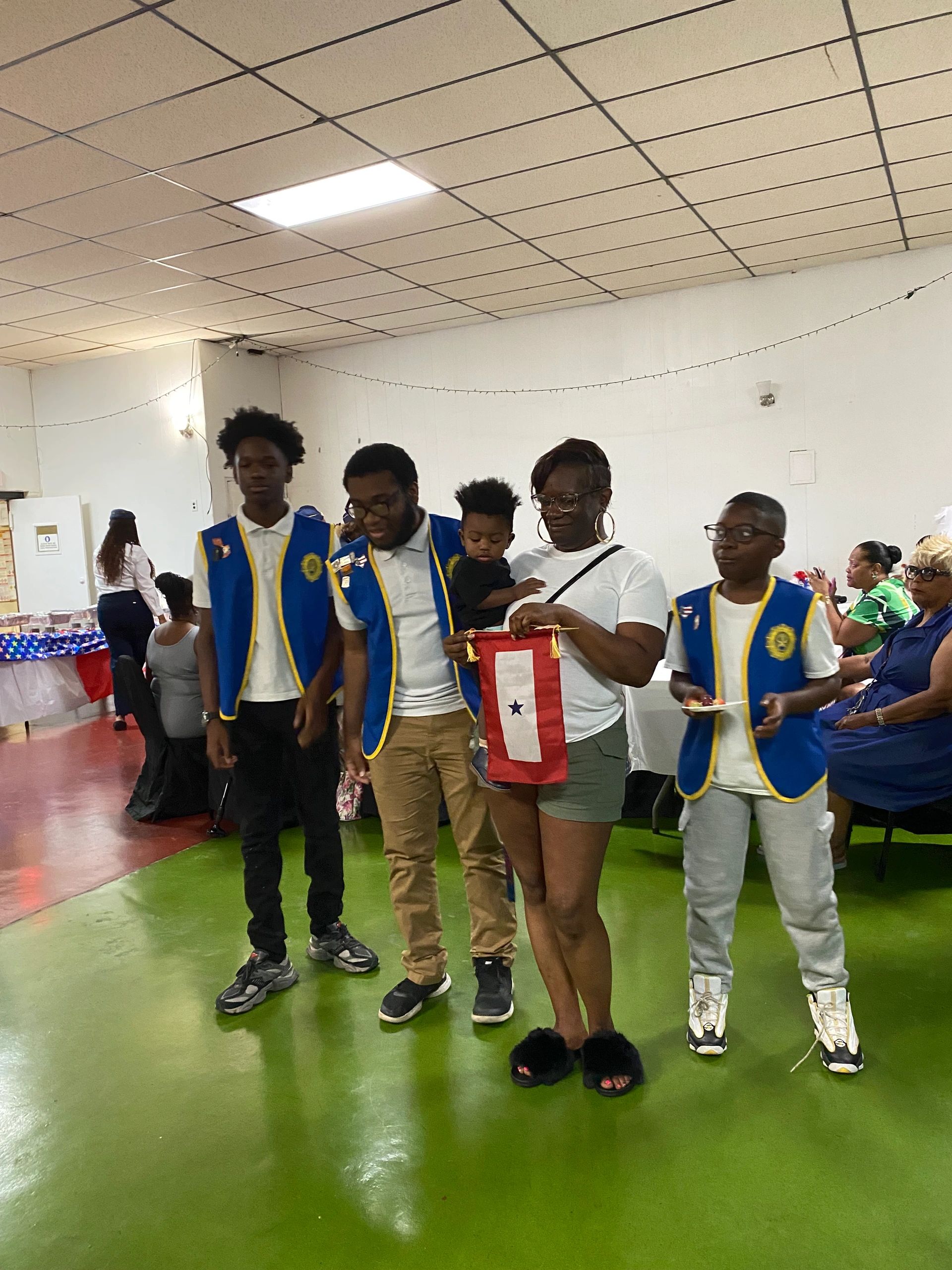 Group of people at an indoor event with some wearing blue vests.