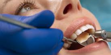 Close-up of dental examination with tools and blue-gloved hand.
