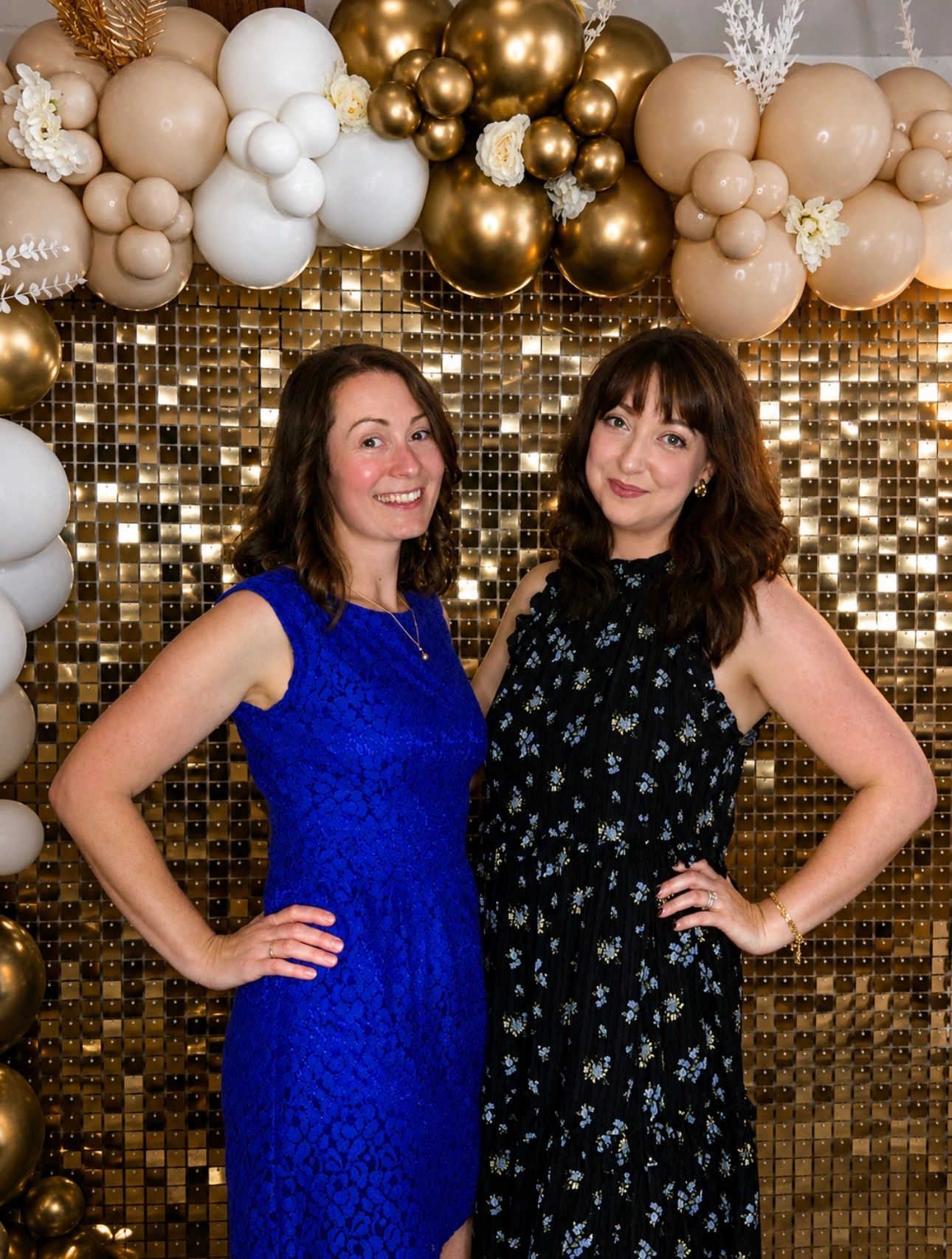 Two guests posing in front of a gold shimmer backdrop and luxury balloon display at a Crystal Clear 