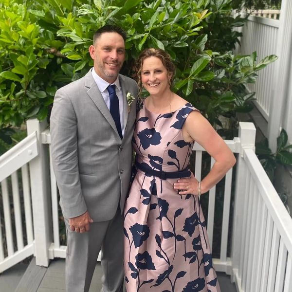 A smiling couple dressed formally standing outdoors.