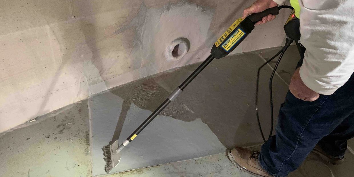 Inspector performing high-voltage holiday testing on a tank lining.