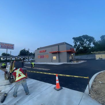 Newly paved Dunkin' drive-thru with workers finishing up.