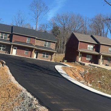 New asphalt road leading to residential houses on a clear day.