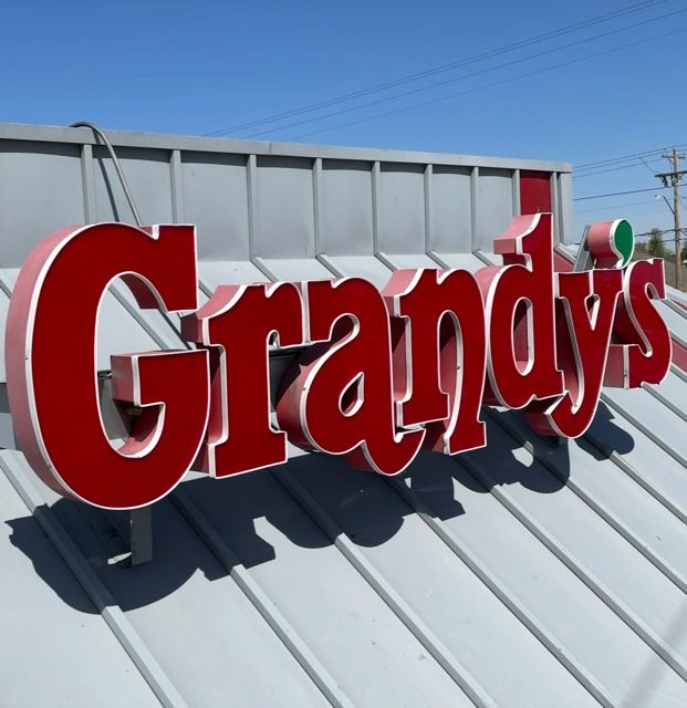 Red Grandy's sign mounted on a gray rooftop under clear blue sky.