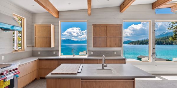 Modern kitchen with wooden cabinets and large windows showcasing a stunning lake view.