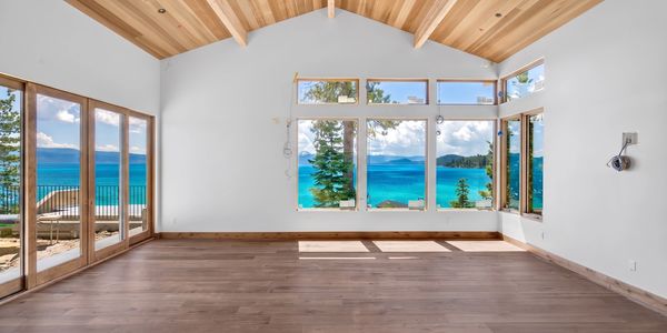 Empty room with large windows showcasing a stunning lake view.