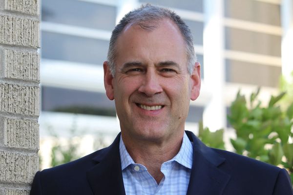 Smiling middle-aged man in a suit standing outdoors.