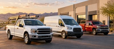 Three pickup trucks and a van parked outside a building at sunset.