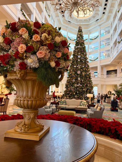 Elegant hotel lobby decorated with a large floral arrangement and a tall Christmas tree.
