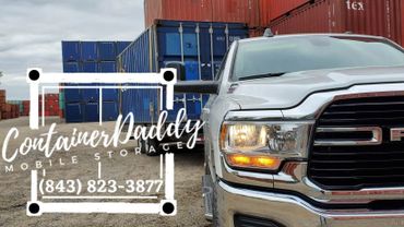 Pickup truck parked near stacked shipping containers in a storage yard.