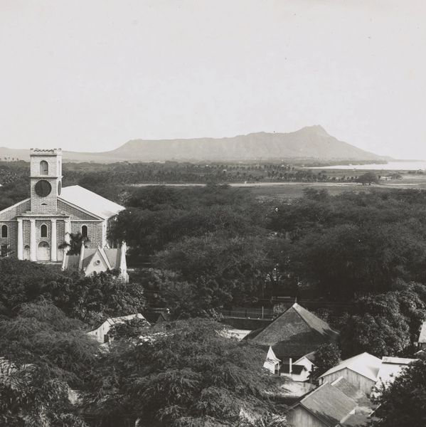 Historic church surrounded by lush trees with a mountain in the background.