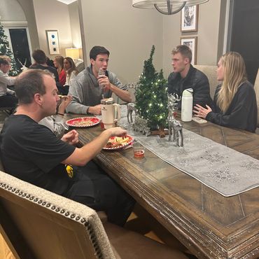 Friends enjoying a festive holiday gathering around a decorated dining table.