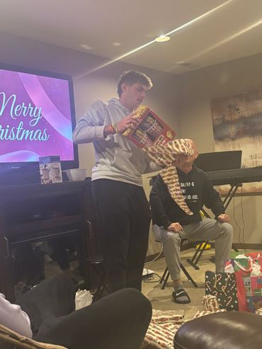 Two people exchanging Christmas gifts in a cozy living room.