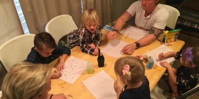 Children and an adult doing crafts at a table.