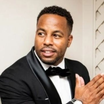 Man in a black tuxedo with a bow tie looking to the side.