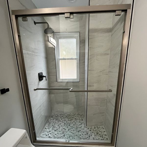 Modern bathroom with glass shower and pebble floor tiles.