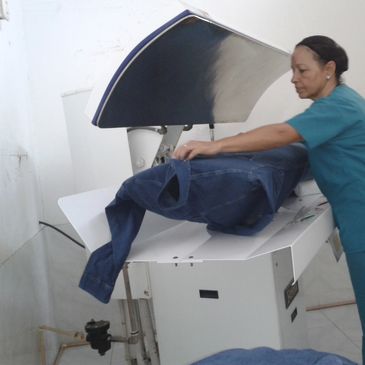 A woman ironing a pair of jeans on a professional ironing machine.