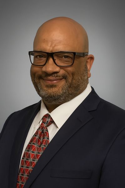Man in glasses and suit smiling.