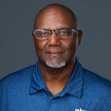 Portrait of a middle-aged man wearing glasses and a blue polo shirt.
