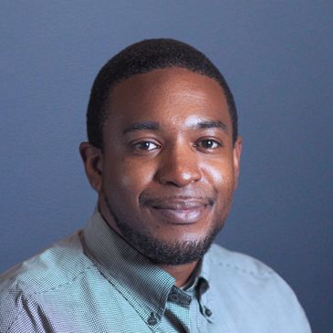 Portrait of a man smiling against a plain blue background.
