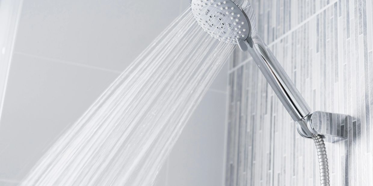 Showerhead spraying water in the shower of a bathroom. 