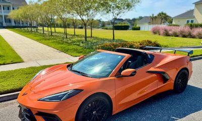Orange convertible sports car parked on a sunny suburban street.