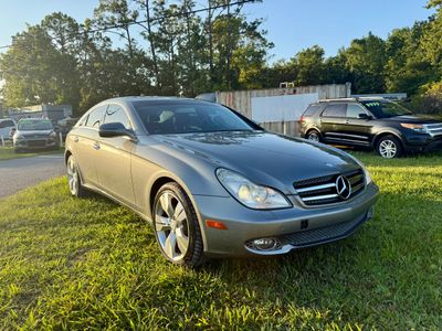 Silver Mercedes-Benz sedan parked on grass in sunlight.