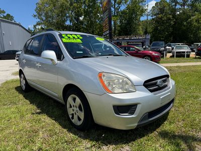 Silver Kia hatchback displayed for sale on grass lot.