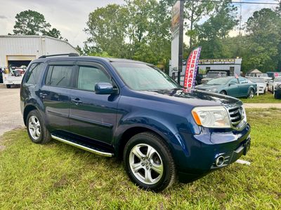 Blue mid-size SUV parked on grass near auto dealership.