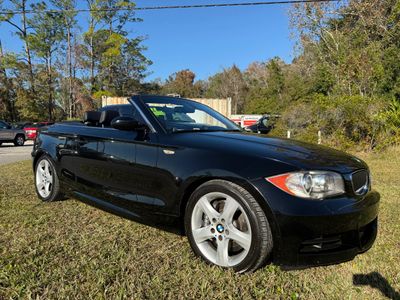 Black BMW convertible parked on grass under clear blue sky.
