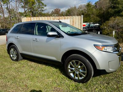 Silver SUV parked on grass with trees and containers in the background.