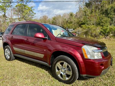 Maroon SUV parked on grass with trees in the background.