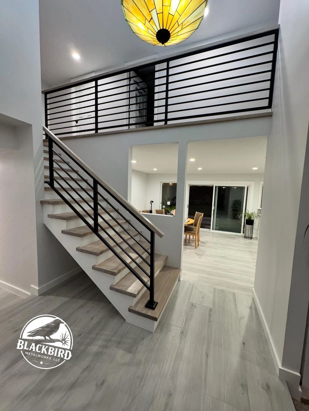 Modern staircase with black metal railings in a bright, minimalist home.