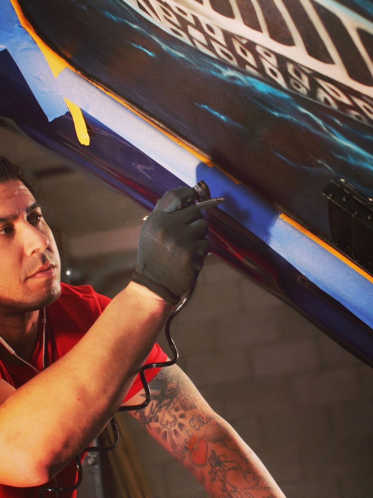 Airbrush artist painting a metal cobra with flames on a headliner of a Shelby GT super snake 