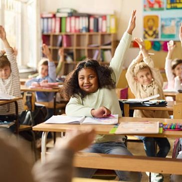 Students raising hands in classroom.