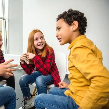 Children sitting and chatting happily indoors.