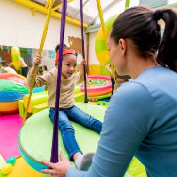 A child on a swing while interacting with an adult.