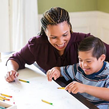 Woman and boy drawing together, smiling.