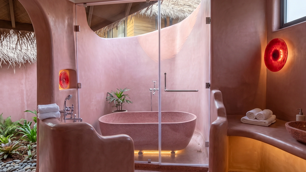 Luxurious pink bathroom with freestanding tub and natural light.