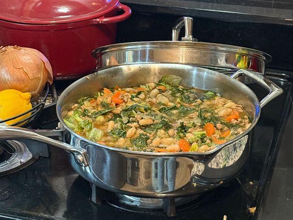 A pot of vegetable and bean stew cooking on the stove.