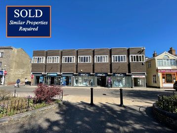 Commercial building with 'Sold' sign under a clear blue sky.