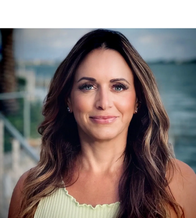 Portrait of a smiling woman with long hair by the water.