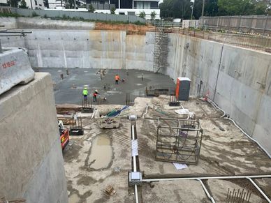 Construction workers pouring concrete in a large foundation pit.